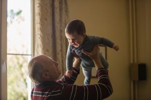 Elderly man holding a baby above his head
