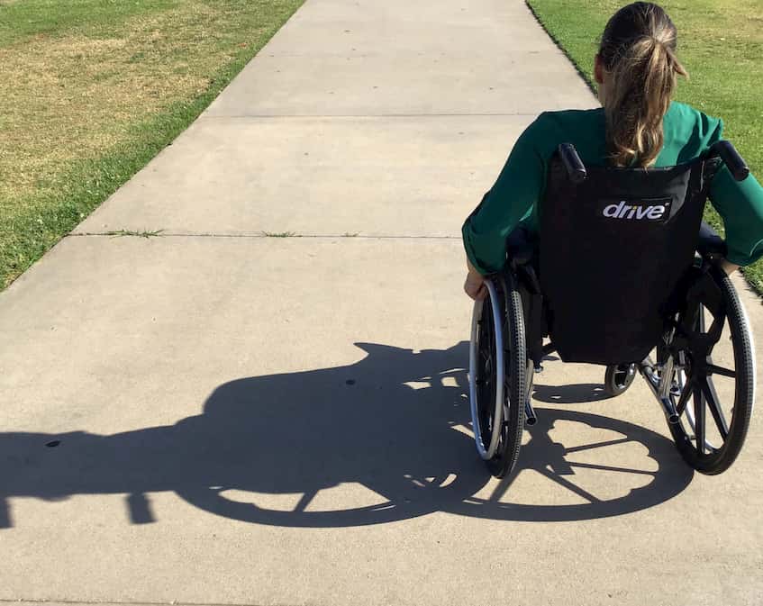 Woman in wheelchair on outdoor footpath