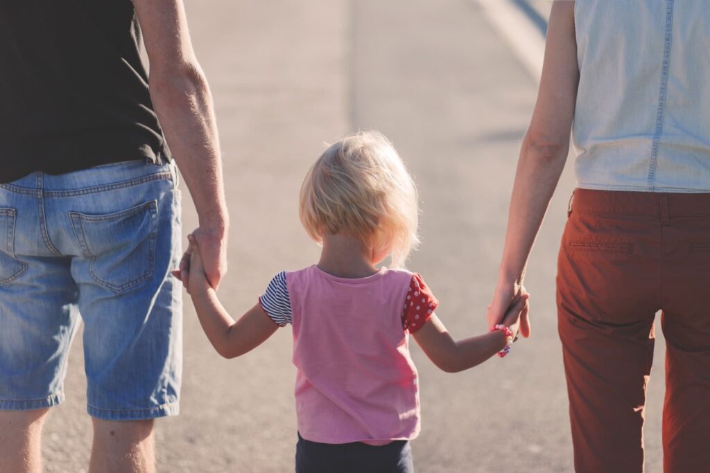 Two parents holding their daughters hand